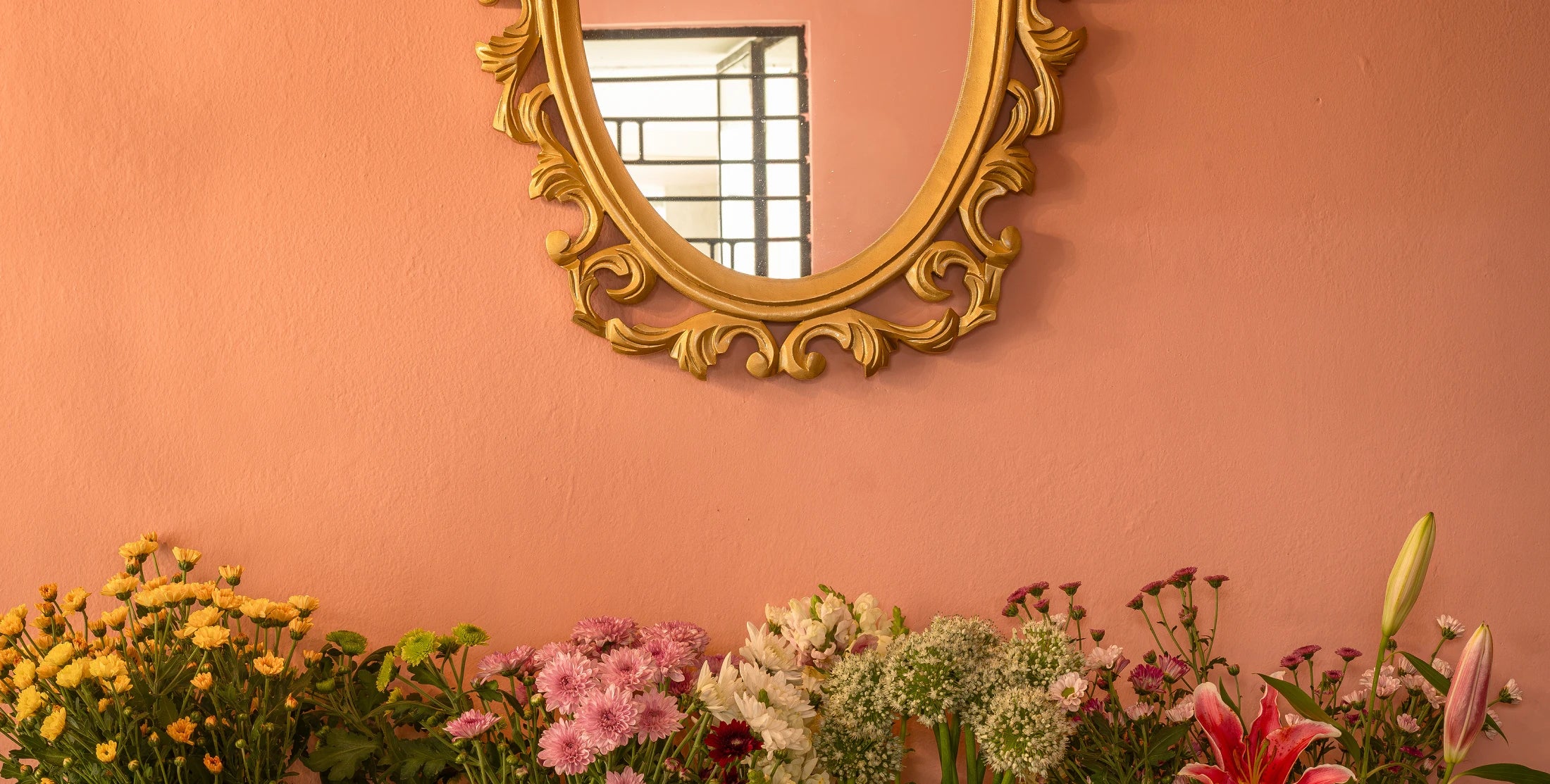 Flowers beneath a gold mirror at Monica's Flowerdeli